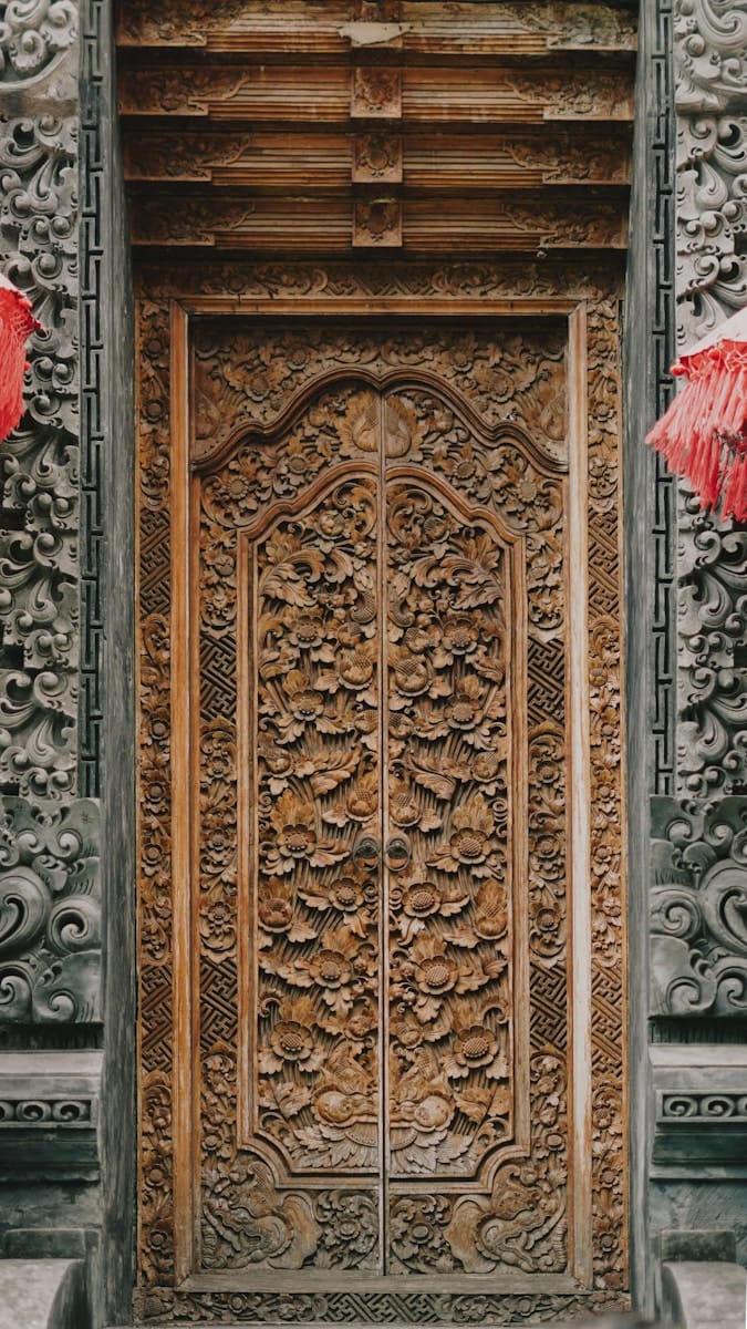 an ornate wooden door with red umbrellas hanging from it